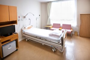 医療用ベッドと家具が配置された清潔感のある居室。大きな窓からの採光が良い。